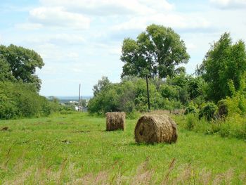 Hay bales on field against sky