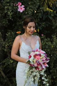 Portrait of marriad woman with pink flower standing against plants in a wedding nature