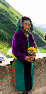 Portrait of young woman standing against mountain