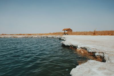 Hut on lakeshore against clear sky at atacama desert