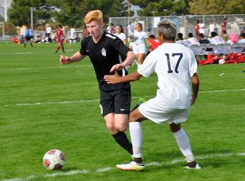 Full length of friends playing soccer on field