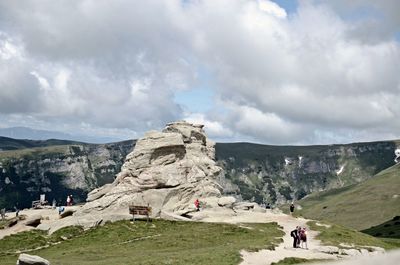 People on rock formations against sky