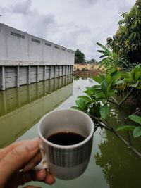 Midsection of person holding coffee cup against sky