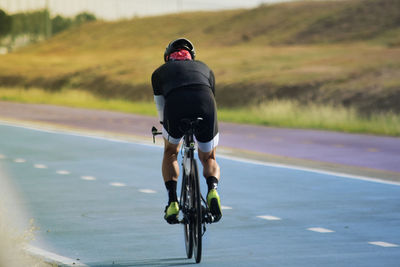 Rear view of man riding bicycle on road