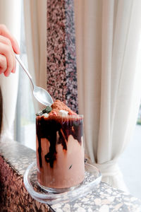 Close-up of hand holding drink on table