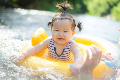 Close-up portrait of cheerful baby girl on inflatable ring in swimming pool