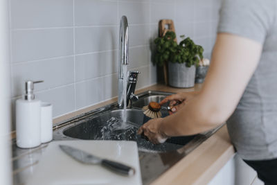 Woman's hands washing dishes in kitchen sink