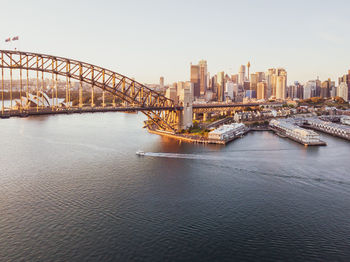 Bridge over river by buildings against clear sky