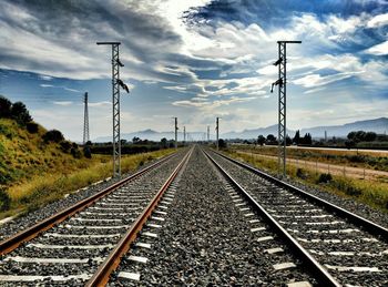 Railroad tracks against cloudy sky