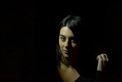 Portrait of young woman against black background