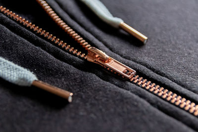 Copper colored fashion zipper macro view showing black sweatshirt with partial opened metal zipper