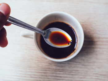 Close-up of hand holding tea cup on table