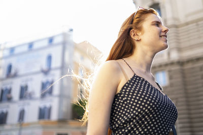 Positive young woman walking on street on summer day