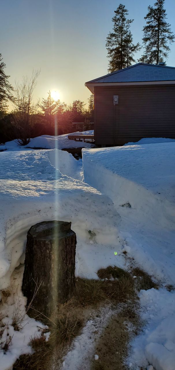 SNOW COVERED FIELD BY BUILDING AGAINST SKY