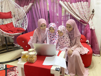 Portrait of a family sitting together at home looking at computer as a  broadband  concept 