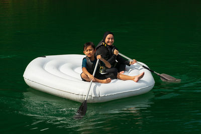 Portrait of mother and son sitting on boat in lake