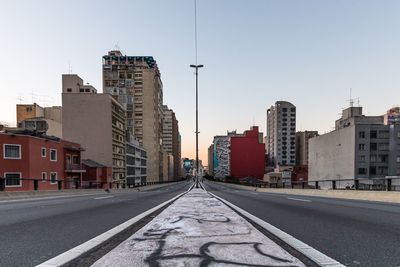 Road amidst buildings in city against clear sky