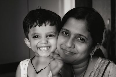 Portrait of smiling mother and daughter at home