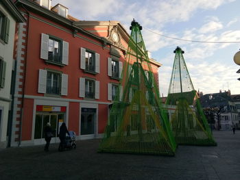 People on street by buildings against sky