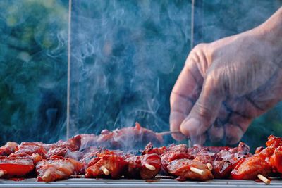 Close-up of person preparing food on barbecue grill