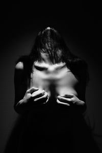 Seductive woman holding breast against black background