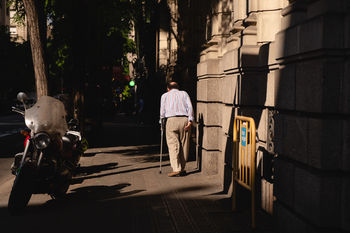 REAR VIEW OF MEN WALKING ON STREET AMIDST BUILDINGS