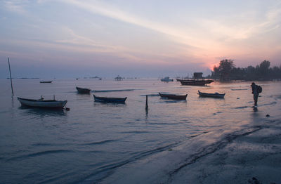 Boats moored on sea against sky during sunset