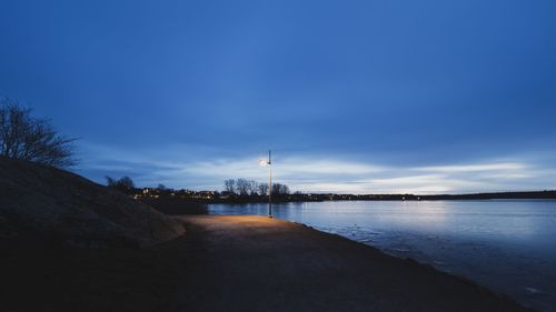 Silhouette of buildings at beach against cloudy sky