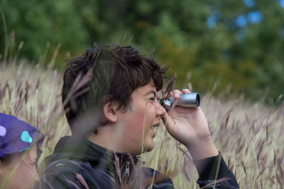 Side view of young man photographing through camera