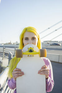 Portrait of woman holding umbrella against clear sky