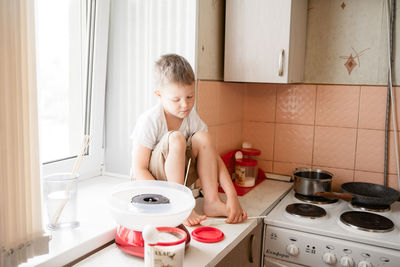 Full length of boy sitting on kitchen at home