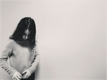 Woman holding top while standing against wall