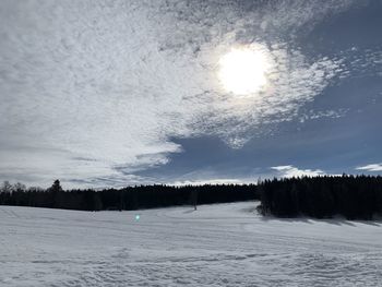 Snow covered land and trees against sky during winter