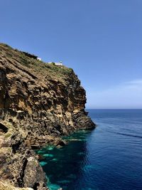 Rock formations in sea against clear blue sky