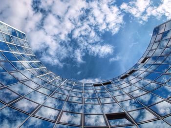 Low angle view of modern building against cloudy sky