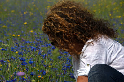 Rear view of girl playing with flowers