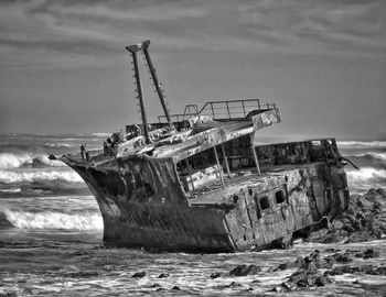 Abandoned boat in sea against sky