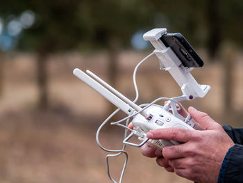 Cropped hands of person using drone remote control and mobile phone 