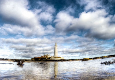 Lighthouse by sea against sky