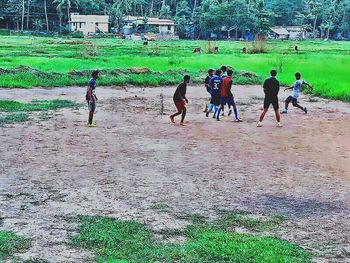 People playing soccer on field against sky