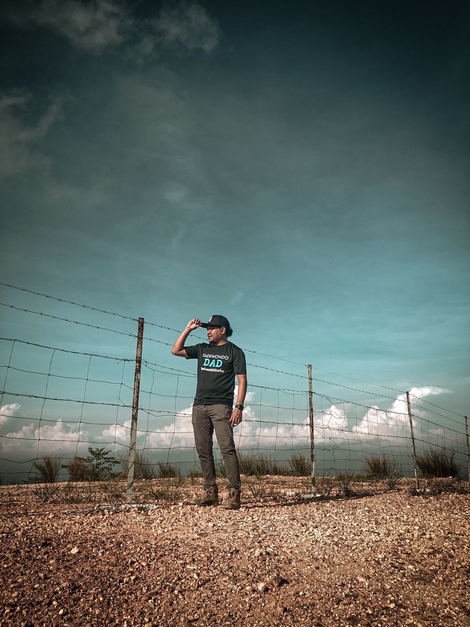 one person, sky, full length, standing, nature, horizon, cloud, sports, sunlight, adult, fence, young adult, blue, morning, copy space, person, casual clothing, land, men, outdoors, lifestyles, day, leisure activity, sea, environment, clothing, light