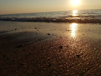 Surface level of beach against sky during sunset