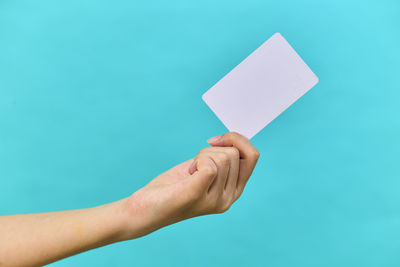 Cropped hand holding slate against blue background