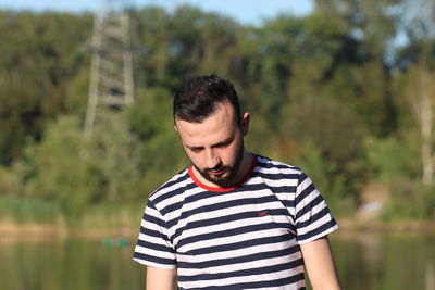 Portrait of young man standing against trees