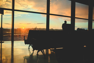 Rear view of man sitting on chairs at sunset