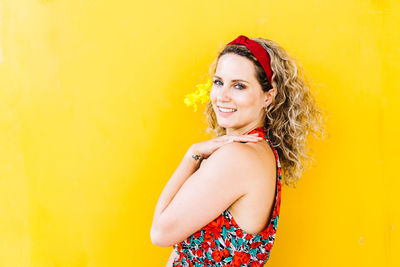 Portrait of a smiling young woman against yellow background