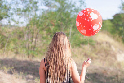 Rear view of woman with red balloon