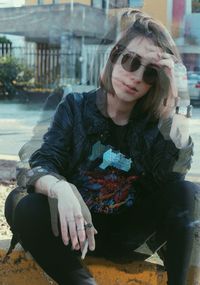 Young woman wearing sunglasses sitting outdoors