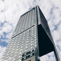 Low angle view of modern building against cloudy sky