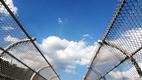 Low angle view of railing against cloudy blue sky on sunny day